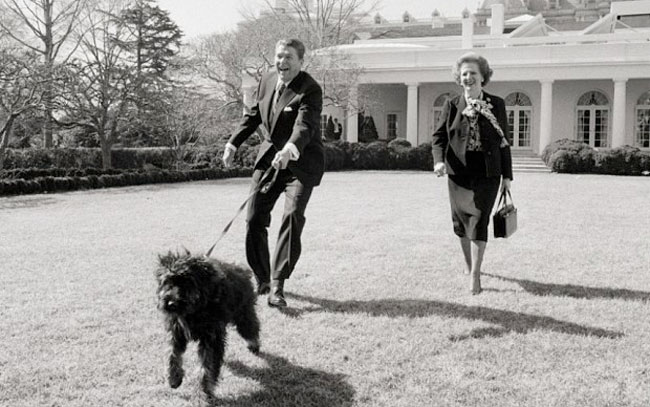 Lucky the dog dragging President Reagan across the lawn. Margaret Thatcher looks on laughing.